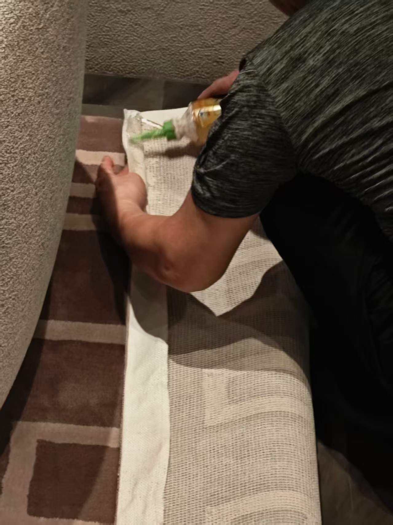 Fitter working on the exposed edge binding of a hotel carpet