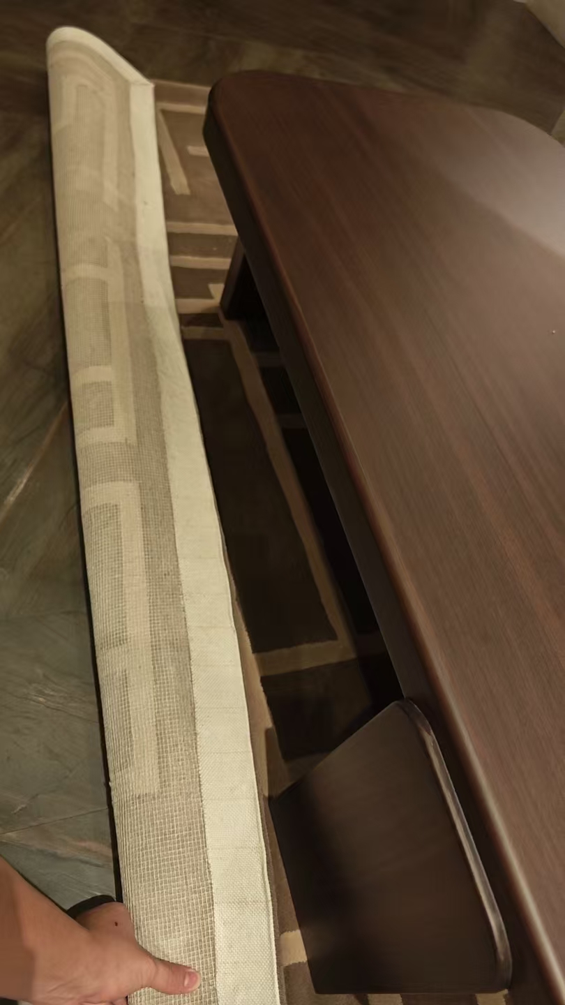 Carpet corner lifted to show white binding tape and grid backing